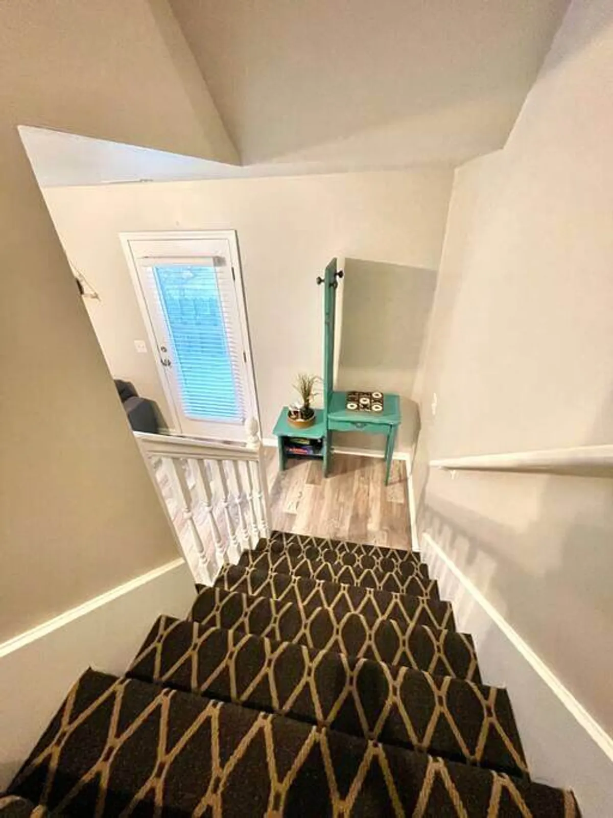 A view of the townhouse entryway featuring a welcoming staircase, a decorative table with thoughtful accents, and a door with a window that hints at the transition between indoor comfort and outdoor adventures.